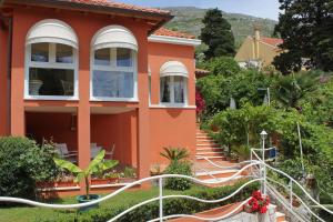a orange house with white windows and stairs at Seaside family friendly house with a swimming pool Mlini, Dubrovnik - 2145 in Mlini