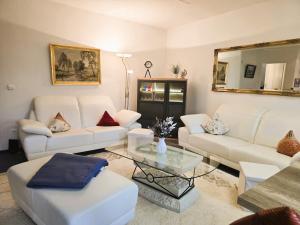 a living room with white couches and a glass table at Ostseeloft Wischuer in Rerik