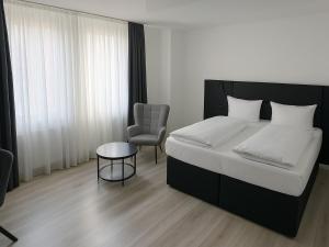 Un dormitorio con una cama, una silla y una mesa. en DORMERO Hotel Dessau-Roßlau, en Dessau