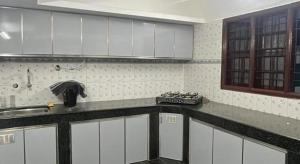 a kitchen with white cabinets and a counter top at RR Villa in Bantvāl