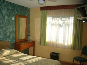 a bedroom with a bed and a dresser and a mirror at Hotel Del Rio Inn in San Luis Potosí