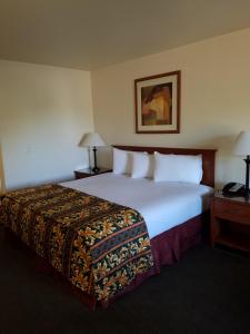 um quarto de hotel com uma cama grande com lençóis brancos em Premier Inns Tolleson em Phoenix