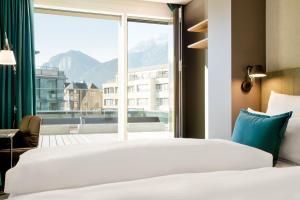 a bedroom with a bed and a large window at Motel One Innsbruck in Innsbruck