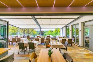 a restaurant with tables and chairs and windows at Hotel Birkenhof in Hanau am Main