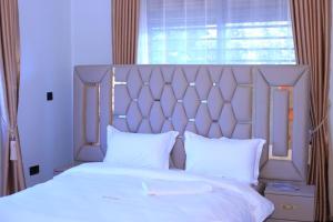 a bedroom with a large bed with white sheets and a window at McMillan Hotel in Entebbe