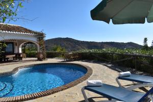 a swimming pool with two chairs and an umbrella at Finca Higueron with private Pool in Río