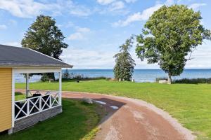 a yellow house with a circular driveway next to the ocean at First Camp Vadstena - Vättern in Vadstena