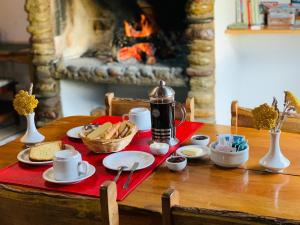 a table with food and coffee on a table with a fireplace at ESTANCIA LA SERENA in Perito Moreno