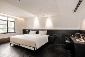 a bedroom with a large white bed and a table at 烟台朝阳文保艺术酒店 in Yantai