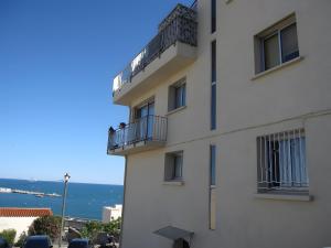 a white building with a balcony and the ocean at Chambre d'hôtes - Le quartier haut in Sète