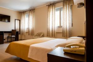 a bedroom with a bed and a desk and windows at Hotiday Conegliano in Conegliano