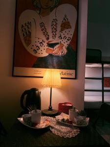 a table with a lamp and a picture of a woman at Europe Station House in Parma