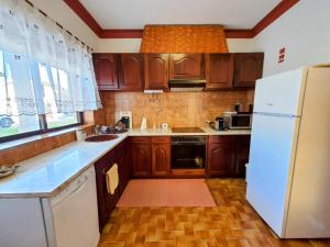 a kitchen with wooden cabinets and a white refrigerator at Casa dos Pomares in Figueira da Foz +3 photos