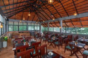 a restaurant with wooden tables and chairs and windows at Citadel Boutique Hotel Thekkady in Jāmb