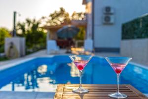 two wine glasses sitting on a table near a swimming pool at Ferienhaus In Opanci Mit Beheiztem Pool, Parkplatz in Lovreć