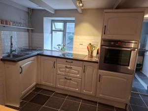 una cucina con armadi bianchi, lavandino e forno di The Samphire Cottage a Porthleven