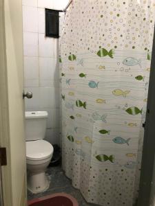 a bathroom with a toilet and a shower curtain with fishes at Den Nest Hostel KRABI in Ban Nong Chaeng