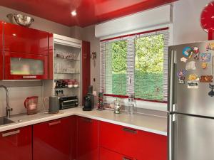a kitchen with red cabinets and a stainless steel refrigerator at Chez Mamie in Hautot-sur-Mer