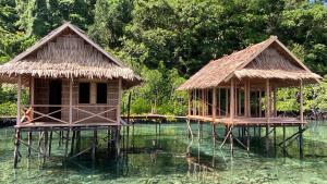 two huts on stilts in a body of water at Batanta Guest House in Pulau Birie +30 photos
