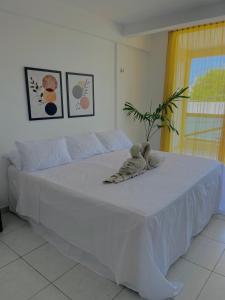 a teddy bear sitting on top of a white bed at Orla Pousada & Café in Parnamirim