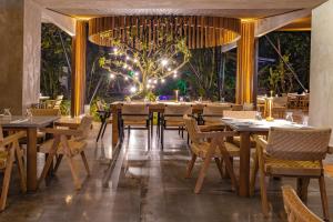 a restaurant with wooden tables and chairs and lights at Noah's Forest Hotel by Tifakara in Fortuna