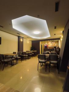 um restaurante com mesas e cadeiras e um tecto branco em Hotel Real em Pristina