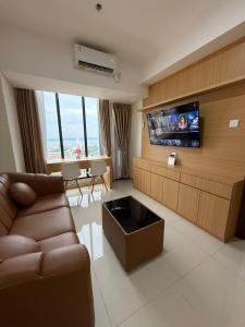Una sala de estar con un sofá y un televisor de pantalla plana. en Modern 1BR with City & Sea View, en Batam Centre