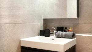 a bathroom with a white sink and a mirror at COSMOPOLITAN APARTMENTS Zürich Seefeld in Zürich +64 photos