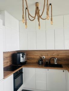 a kitchen with white cabinets and a chandelier at Hevenia Klifowa 5 B Apartament 33 in Rewal