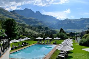 a resort with a pool and mountains in the background at Champagne Castle Hotel in Champagne Valley