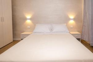 a large white bed in a room with two lights at IL CENTRO rooms in Cerignola +1 photo