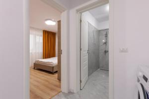 a bathroom with a walk in shower and a bedroom at Urban Retreat 1BDR Craiova in Bordeiu +20 photos