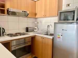 a small kitchen with a refrigerator and a sink at Departamento Playa Cochoa, Reñaca in Viña del Mar