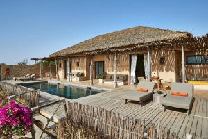 a resort with a pool and a house with a thatch roof at Yokan Lodge in Palmarin