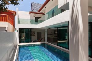 an external view of a house with a swimming pool at Modern Villa 4-BR, Breeze - 10 min walk to NaiYang beach in Nai Yang Beach