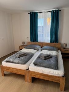 two twin beds in a bedroom with blue curtains at Stadtquartier Völkermarkt in Völkermarkt +2 photos
