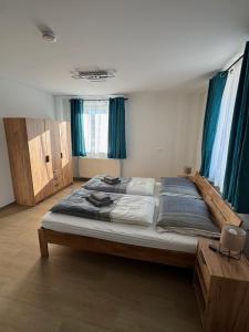 a large bed in a room with blue curtains at Stadtquartier Völkermarkt in Völkermarkt