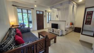 Safina Cottages في شاطئ دياني: غرفة معيشة مع أريكة ومدفأة