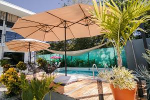 a patio with a table with an umbrella and a pool at Casa Ola Ini Studio Playa Grande in Playa Grande