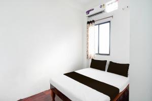 a bedroom with a bed with white walls and a window at SPOT ON Ap Logde in Māharjhari +22 photos