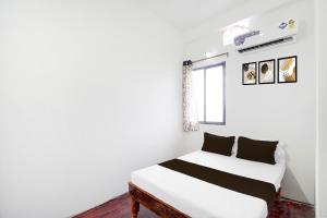 a bedroom with a white bed with black pillows at SPOT ON Ap Logde in Māharjhari