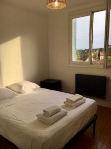 a bedroom with a white bed with towels on it at T3 cozy Saint Genis Laval - balcony - quiet - HLS in Saint-Genis-Laval