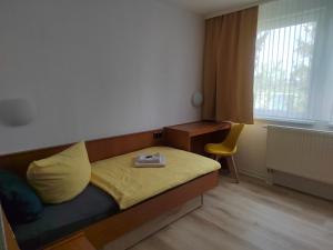 a bedroom with a bed with a yellow pillow and a chair at Pension Schachtblick in Bleicherode