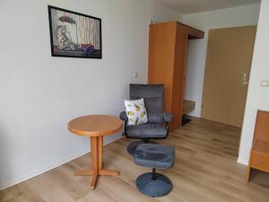 a living room with a chair and a table at Pension Schachtblick in Bleicherode