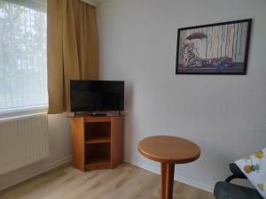 a living room with a television and a stool at Pension Schachtblick in Bleicherode