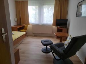 a small room with a bed and a chair at Pension Schachtblick in Bleicherode