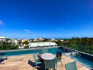 un patio avec une table et des chaises à côté d'une piscine dans l'établissement Flat bijupira exclusive brisa do mar em Porto de galinhas a 100 metros das piscinas naturais, à Porto de Galinhas