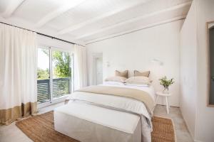 a white bedroom with a large bed and a window at Posada Arenas in José Ignacio