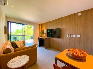 un salon avec un canapé et une télévision dans l'établissement Flat bijupira exclusive brisa do mar em Porto de galinhas a 100 metros das piscinas naturais, à Porto de Galinhas