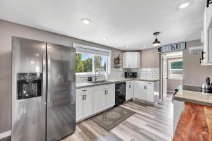 een keuken met witte kasten en een roestvrijstalen koelkast bij Lazy River Villa - Hottub! Fenced Yard! Fire Pit! in Oconto